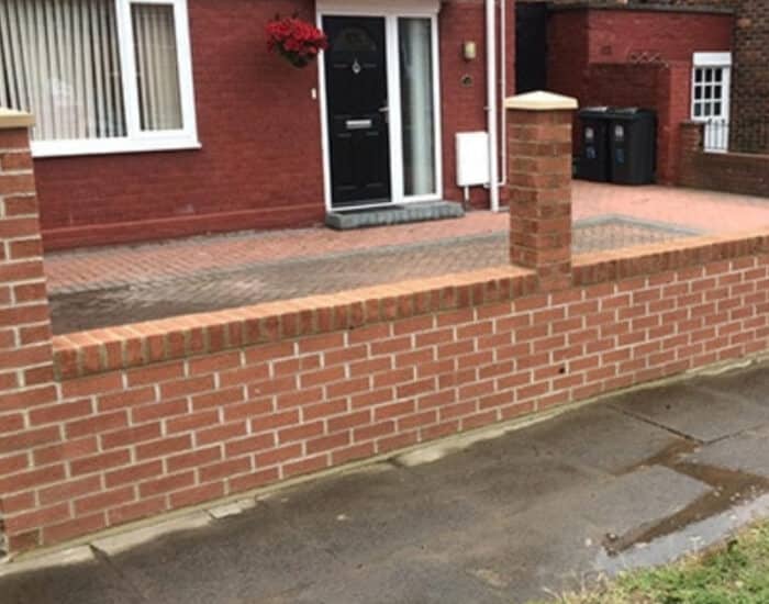 A brick wall featuring a gate and a fence, creating a defined boundary in an outdoor setting.